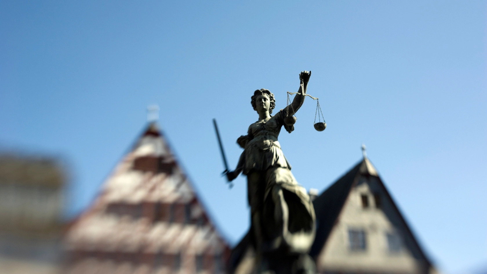 Die Statue von Justizia am Frankfurter Römer, welcher stilistisch unscharf im Hintergrund abgebildet ist