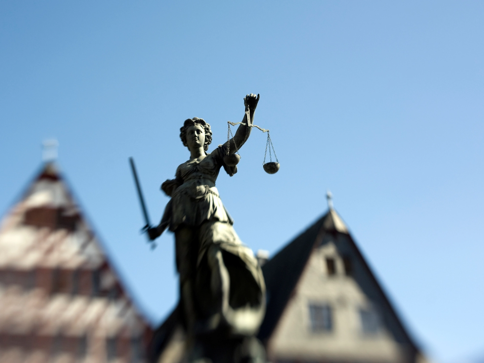 Die Statue von Justizia am Frankfurter Römer, welcher stilistisch unscharf im Hintergrund abgebildet ist